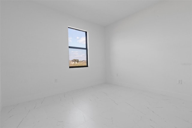 spare room featuring marble look tiles and baseboards