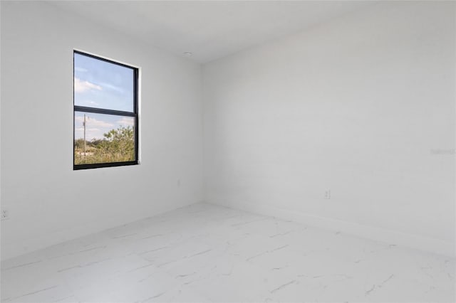 empty room featuring marble finish floors and baseboards