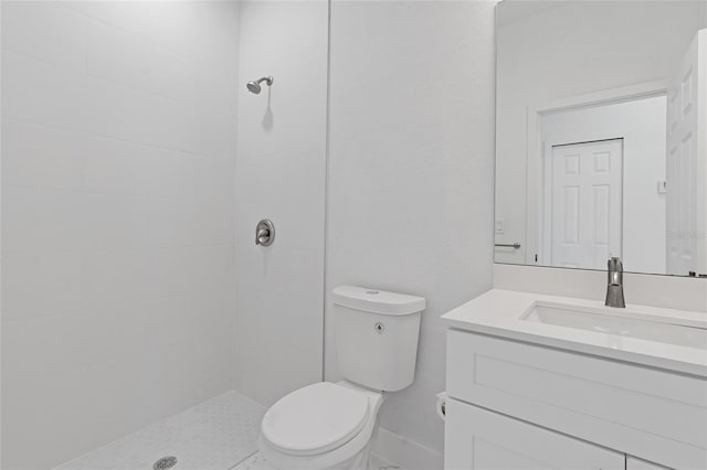 full bathroom with a tile shower, toilet, and vanity