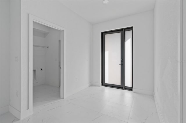 empty room featuring light marble finish floors and baseboards