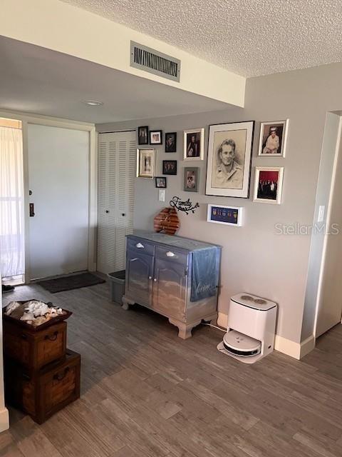 sitting room with wood finished floors, a textured ceiling, and baseboards