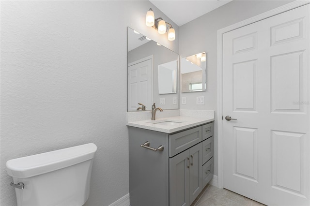bathroom with toilet, vanity, and tile patterned flooring