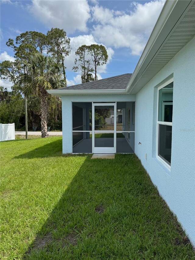 view of green lawn featuring a sunroom