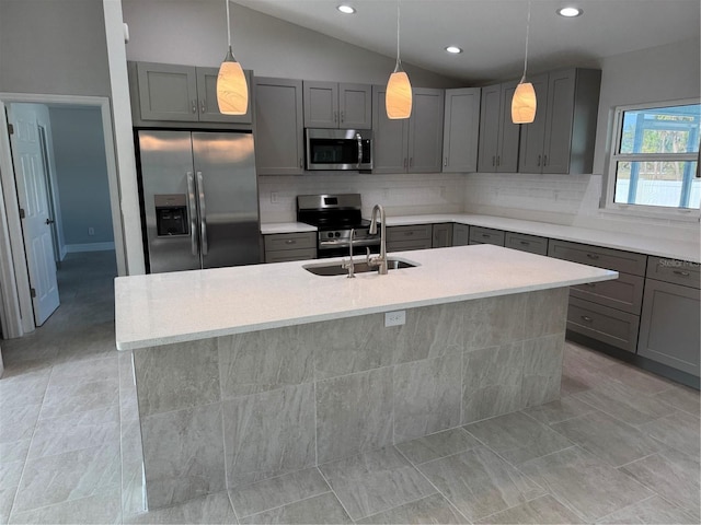 kitchen with appliances with stainless steel finishes, gray cabinets, a sink, decorative backsplash, and lofted ceiling