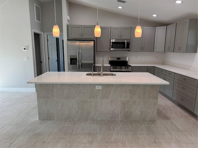 kitchen with appliances with stainless steel finishes, a sink, gray cabinets, lofted ceiling, and backsplash