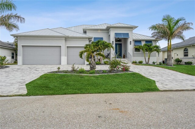 1306 Osprey Dr, Punta Gorda, FL 33950 - view of front facade featuring a standing seam roof, stucco siding, decorative driveway, and an attached garage