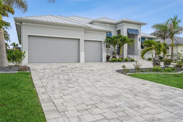 1306 Osprey Dr, Punta Gorda, FL 33950 - view of front of house with a standing seam roof, stucco siding, decorative driveway, an attached garage, and metal roof