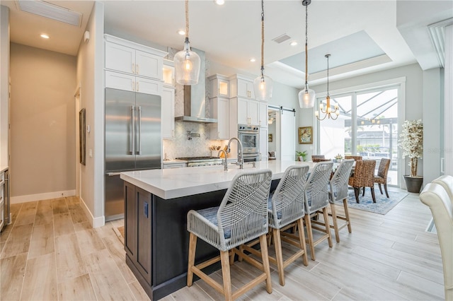 1306 Osprey Dr, Punta Gorda, FL 33950 - kitchen with stainless steel appliances, a barn door, decorative backsplash, a center island with sink, and white cabinets