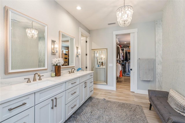 1306 Osprey Dr, Punta Gorda, FL 33950 - full bathroom with a chandelier, wood finished floors, double vanity, a walk in closet, and recessed lighting