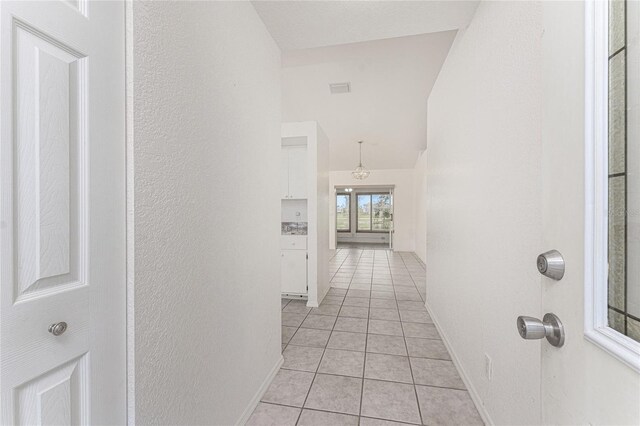 25046 Doredo Dr, Punta Gorda, FL 33955 - hall with light tile patterned flooring, baseboards, and vaulted ceiling