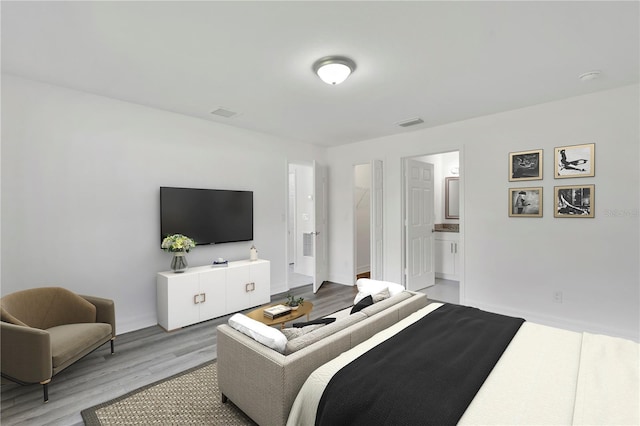 bedroom featuring light wood finished floors, baseboards, and connected bathroom