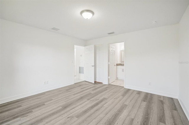 unfurnished bedroom featuring light wood finished floors, baseboards, and connected bathroom