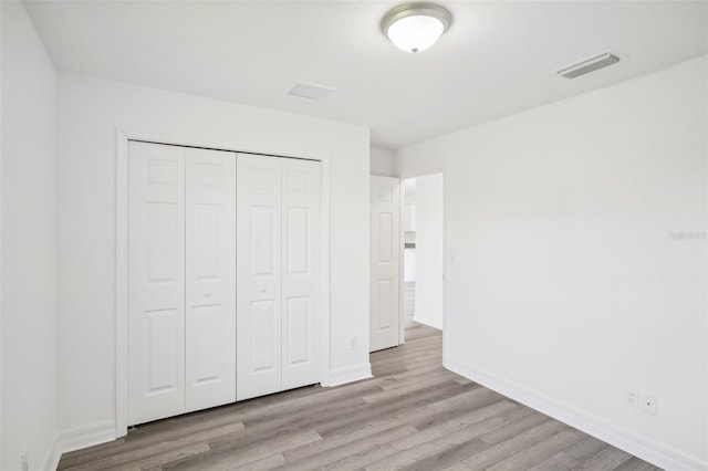 unfurnished bedroom with wood finished floors, baseboards, and a closet