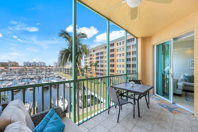 balcony featuring view of marina, a water view, and a ceiling fan