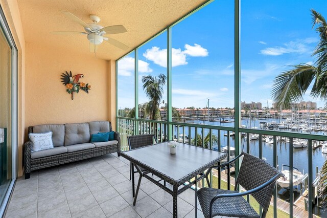 sunroom / solarium with a water view, ceiling fan, view of marina, and an outdoor living space