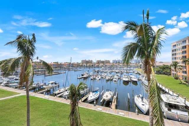 dock area featuring view of marina, a water view, boat lift, and a lawn
