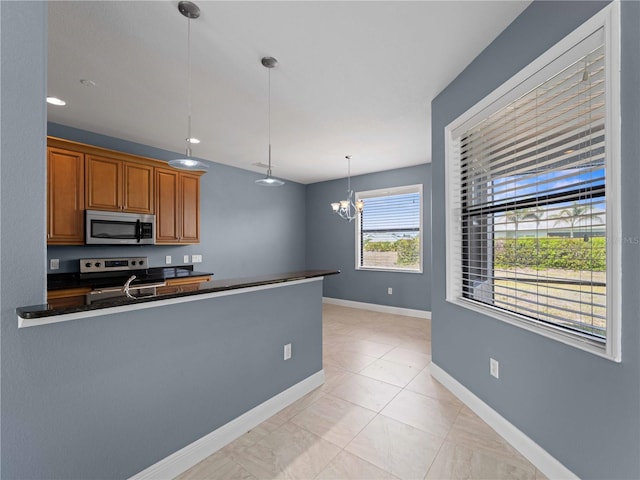 97 Pine Valley Ln, Rotonda West, FL 33947 - kitchen featuring appliances with stainless steel finishes, dark countertops, brown cabinetry, hanging light fixtures, and baseboards