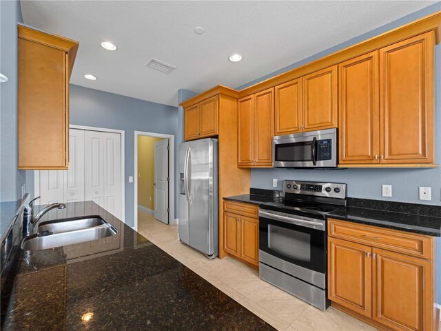 97 Pine Valley Ln, Rotonda West, FL 33947 - kitchen with stainless steel appliances, a sink, dark stone counters, brown cabinetry, and recessed lighting