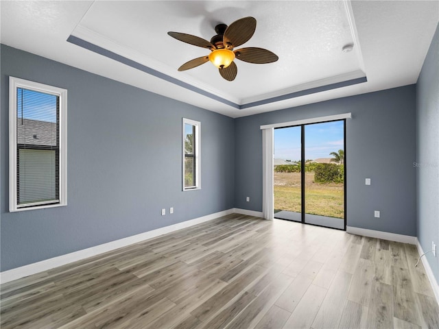 97 Pine Valley Ln, Rotonda West, FL 33947 - unfurnished room with a raised ceiling, light wood-style floors, baseboards, a ceiling fan, and a smoke detector