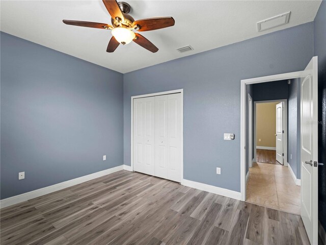 97 Pine Valley Ln, Rotonda West, FL 33947 - unfurnished bedroom with wood finished floors, a closet, baseboards, and ceiling fan