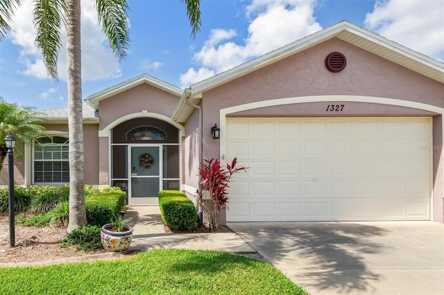 view of front of home featuring stucco siding, driveway, and a garage