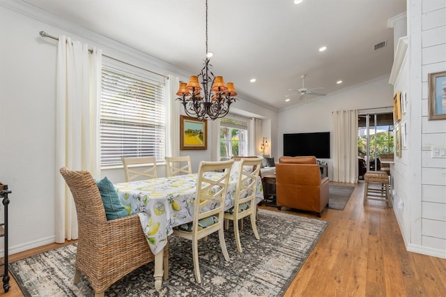 dining area featuring a chandelier, light wood finished floors, vaulted ceiling, crown molding, and ceiling fan