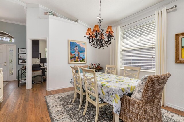 dining space with a chandelier, light wood finished floors, lofted ceiling, baseboards, and crown molding
