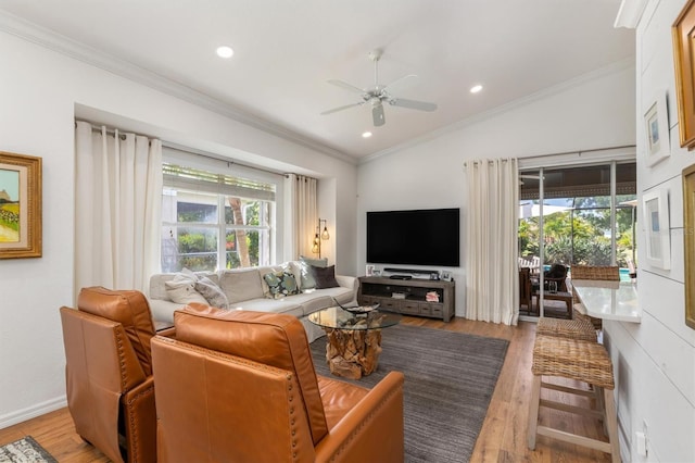 living room featuring plenty of natural light, ornamental molding, ceiling fan, light wood finished floors, and vaulted ceiling