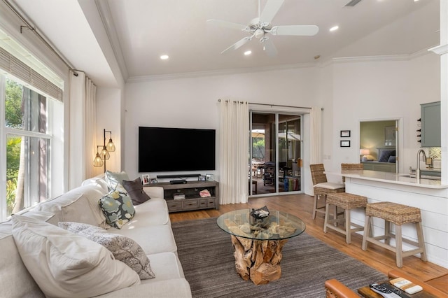 living room featuring plenty of natural light, crown molding, wood finished floors, a ceiling fan, and high vaulted ceiling