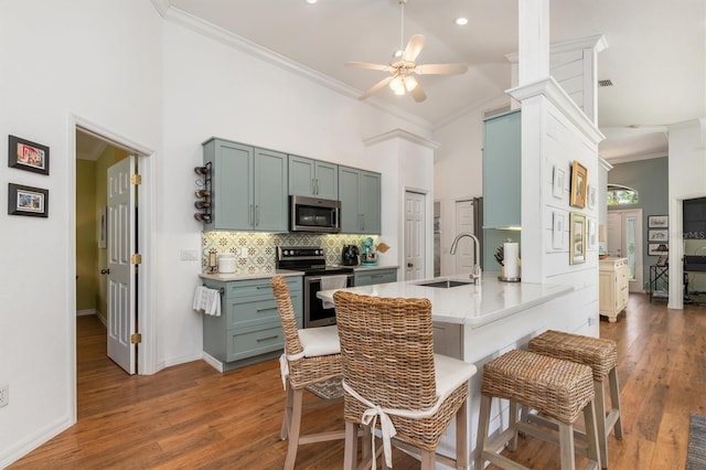 kitchen with appliances with stainless steel finishes, a sink, high vaulted ceiling, a ceiling fan, and backsplash