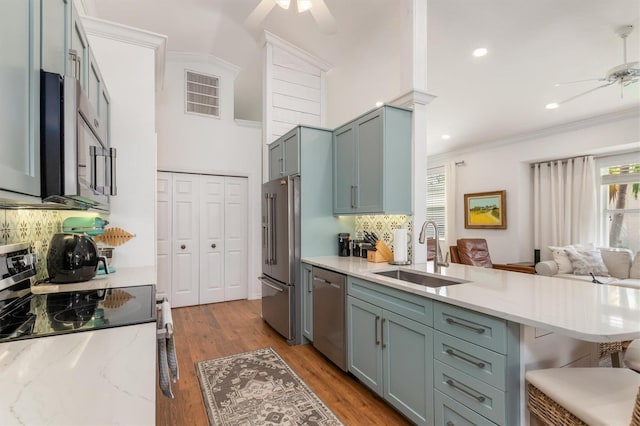 kitchen featuring a ceiling fan, a sink, stainless steel appliances, tasteful backsplash, and crown molding