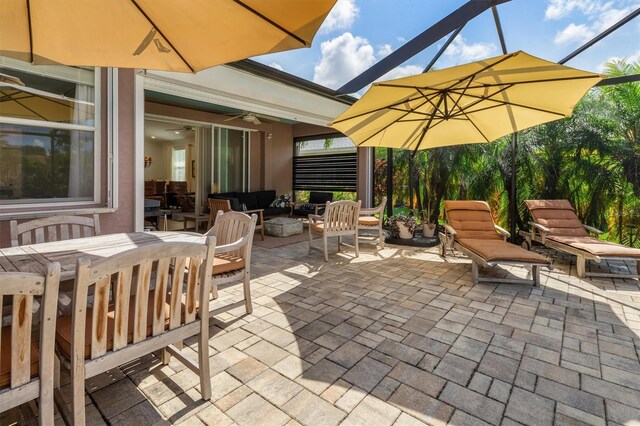 view of patio / terrace featuring an outdoor hangout area, outdoor dining area, a ceiling fan, and a lanai