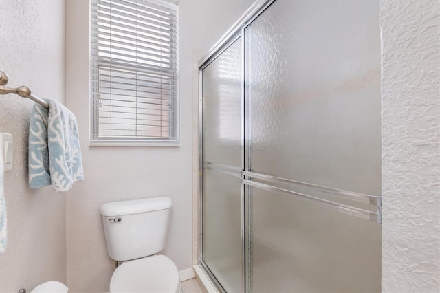 full bathroom featuring a shower with door and toilet