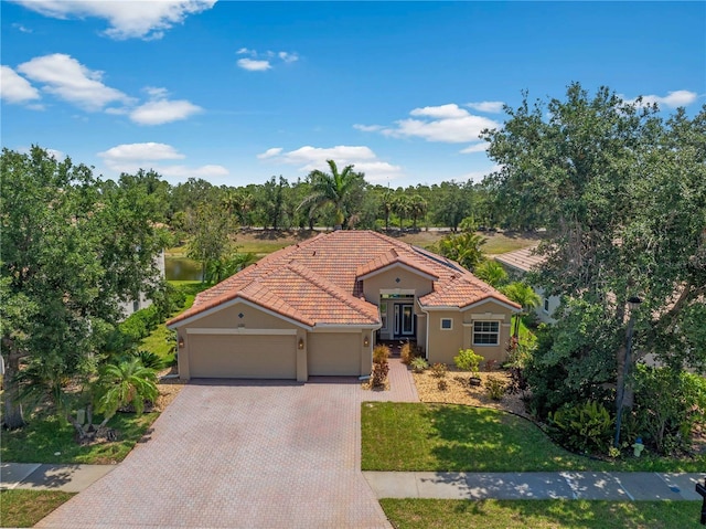 11982 Granite Woods Loop, Venice, FL 34292 - mediterranean / spanish home featuring a tile roof, a garage, decorative driveway, and stucco siding
