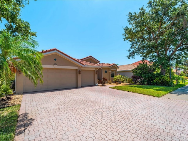 11982 Granite Woods Loop, Venice, FL 34292 - mediterranean / spanish house with stucco siding, decorative driveway, an attached garage, and a tile roof