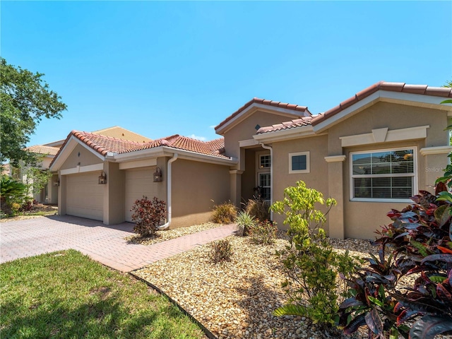 11982 Granite Woods Loop, Venice, FL 34292 - mediterranean / spanish-style house with stucco siding, a garage, a tile roof, and decorative driveway