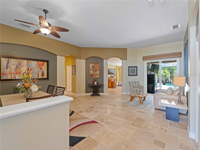 11982 Granite Woods Loop, Venice, FL 34292 - living area with arched walkways, ceiling fan, stone tile floors, and baseboards