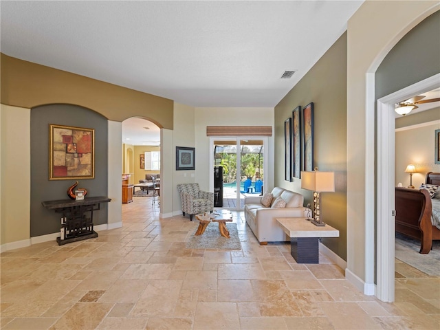 11982 Granite Woods Loop, Venice, FL 34292 - living area with arched walkways, stone tile floors, baseboards, and ceiling fan