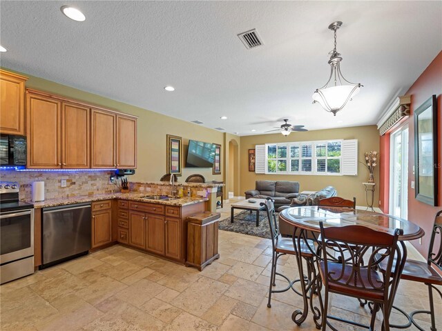 11982 Granite Woods Loop, Venice, FL 34292 - kitchen featuring appliances with stainless steel finishes, a peninsula, stone tile floors, a sink, and recessed lighting