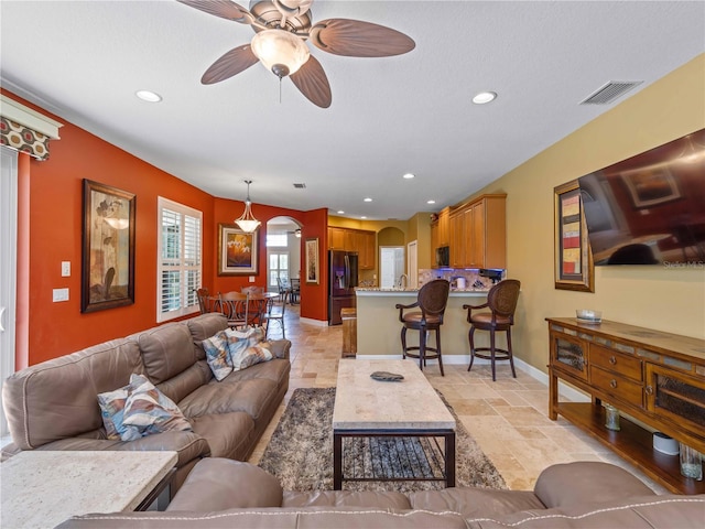11982 Granite Woods Loop, Venice, FL 34292 - living room featuring arched walkways, stone tile flooring, recessed lighting, a ceiling fan, and baseboards