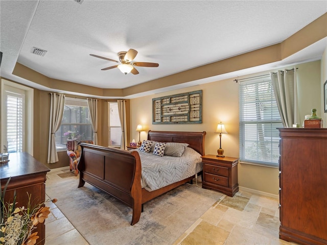 11982 Granite Woods Loop, Venice, FL 34292 - bedroom featuring light stone finish flooring, baseboards, a textured ceiling, and a ceiling fan