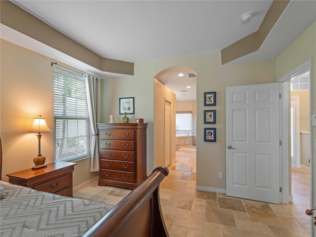 11982 Granite Woods Loop, Venice, FL 34292 - bedroom with arched walkways, stone tile floors, multiple windows, baseboards, and a textured ceiling