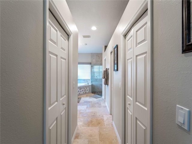 11982 Granite Woods Loop, Venice, FL 34292 - hall featuring stone tile floors, a textured wall, and recessed lighting