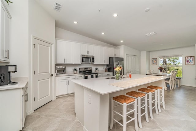 43984 Boardwalk Loop Unit 1726, Punta Gorda, FL 33982 - kitchen with stainless steel appliances, vaulted ceiling, a sink, a center island with sink, and white cabinets