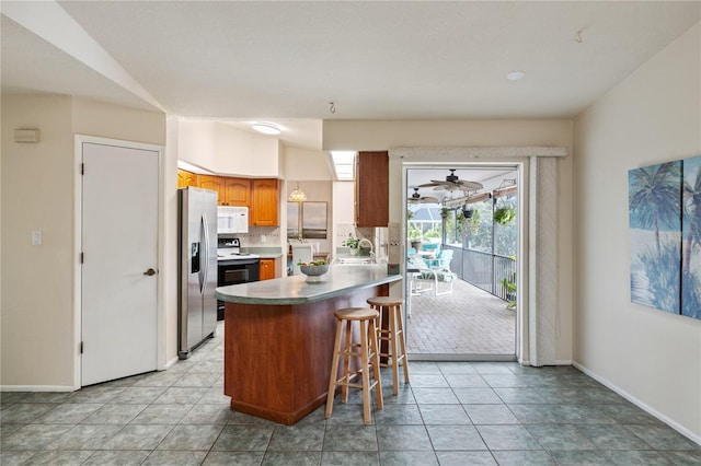 3301 Santa Barbara Dr, Punta Gorda, FL 33983 - kitchen featuring white microwave, stainless steel refrigerator with ice dispenser, a sink, a peninsula, and a breakfast bar