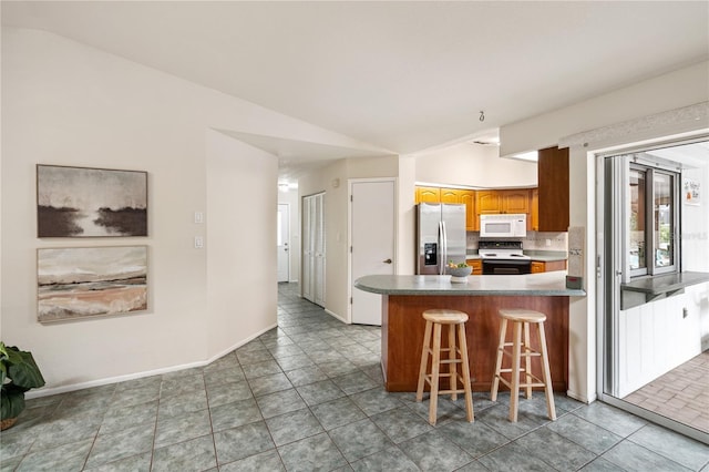 3301 Santa Barbara Dr, Punta Gorda, FL 33983 - kitchen with stainless steel fridge with ice dispenser, white microwave, electric stove, lofted ceiling, and backsplash