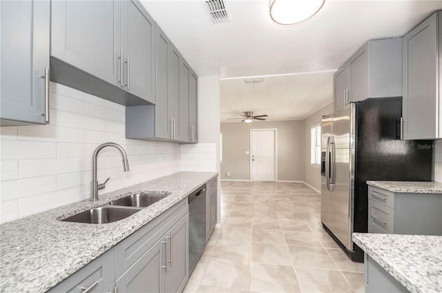 kitchen featuring a sink, stainless steel appliances, ceiling fan, gray cabinetry, and tasteful backsplash