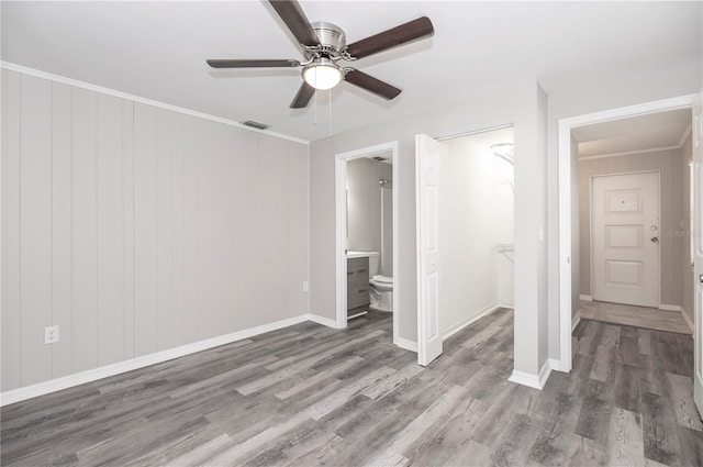 unfurnished bedroom featuring wood finished floors, ceiling fan, baseboards, and ensuite bathroom