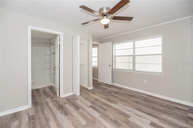unfurnished bedroom with light wood-type flooring, baseboards, ensuite bath, and a ceiling fan