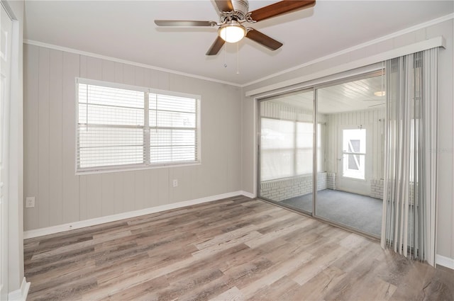 unfurnished bedroom with wood finished floors, a closet, crown molding, baseboards, and a ceiling fan